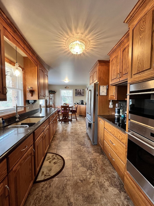 3817 Butterworth St SW, Grand Rapids, MI 49534 - kitchen with appliances with stainless steel finishes, dark countertops, a sink, dark stone finish floors, and brown cabinetry