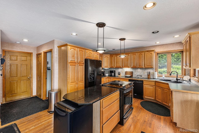 1437 Rillview Ct, Metamora, MI 48455 - kitchen featuring black appliances, a sink, light wood-style floors, a center island, and backsplash
