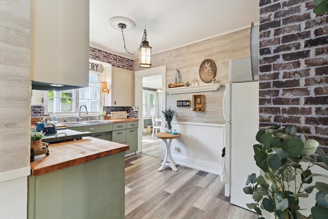 700 S Washington, Mount Pleasant, MI 48858 - kitchen featuring wood counters, green cabinets, light wood-type flooring, a sink, and hanging light fixtures