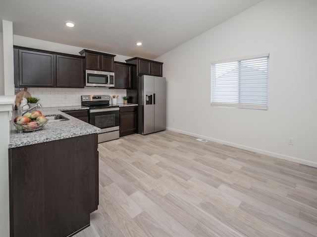 1925 Prescott Trl, Galesburg, MI 49053 - kitchen with stainless steel appliances, vaulted ceiling, backsplash, dark brown cabinets, and light stone counters