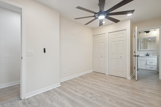 932 Enders Ave, Benton Harbor, MI 49022 - unfurnished bedroom with two closets, light wood-style flooring, a sink, baseboards, and ceiling fan