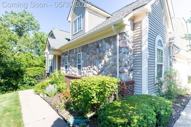 2062 Preserve Cir W, Canton, MI 48188 - view of home's exterior with a garage, stone siding, and roof with shingles