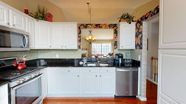 17 E Drake Dr, Saginaw, MI 48603 - kitchen featuring stainless steel appliances, a chandelier, backsplash, white cabinetry, and vaulted ceiling
