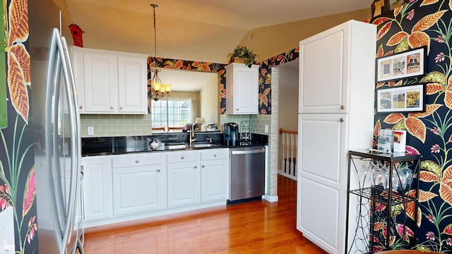 17 E Drake Dr, Saginaw, MI 48603 - kitchen featuring stainless steel appliances, dark countertops, a chandelier, light wood-style floors, and tasteful backsplash