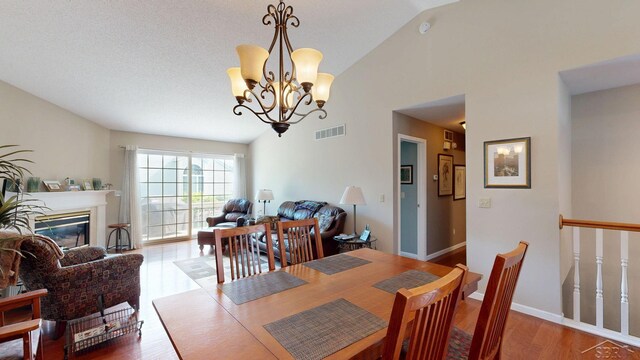 17 E Drake Dr, Saginaw, MI 48603 - dining space with wood finished floors, a chandelier, a glass covered fireplace, high vaulted ceiling, and baseboards