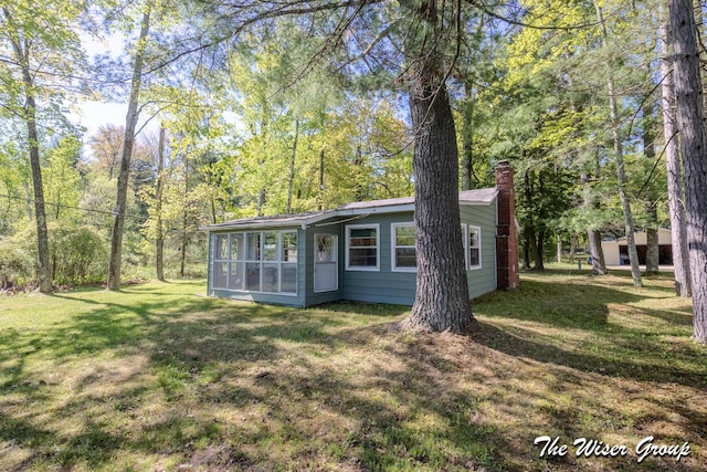 1261 W Channel St, Bitely, MI 49309 - view of front of home featuring a sunroom, a chimney, and a front lawn