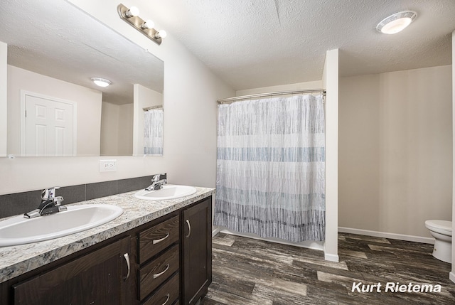 532 48th St, Grand Junction, MI 49056 - full bathroom with wood finished floors, double vanity, toilet, a textured ceiling, and curtained shower