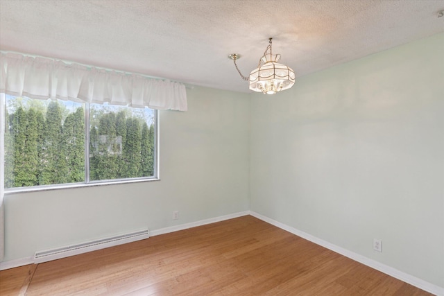 530 Manitou Rd, Saint Joseph, MI 49085 - unfurnished room with baseboard heating, a chandelier, wood finished floors, baseboards, and a textured ceiling