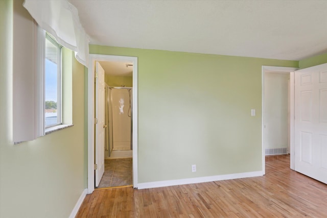 530 Manitou Rd, Saint Joseph, MI 49085 - unfurnished bedroom with light wood-style floors, baseboards, multiple windows, and connected bathroom