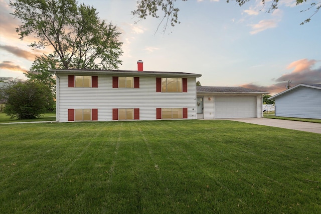 530 Manitou Rd, Saint Joseph, MI 49085 - tri-level home with concrete driveway, a front yard, an attached garage, and a chimney