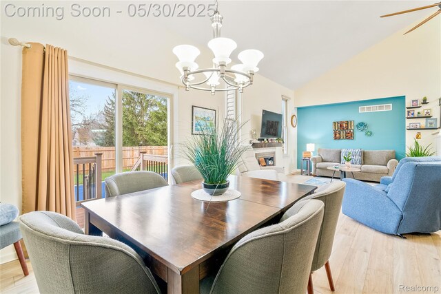 454 Breakwater, Belleville, MI 48111 - dining area with a chandelier, light wood finished floors, high vaulted ceiling, and a fireplace
