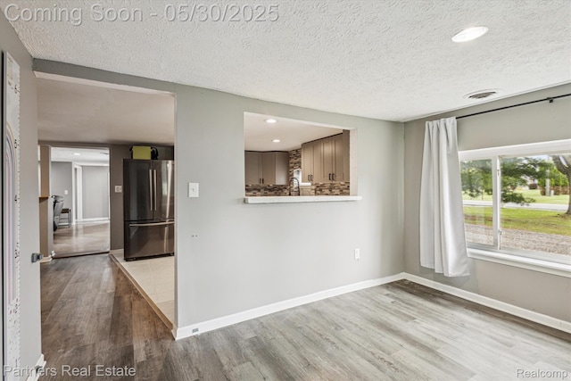 11651 Mason Rd, Webberville, MI 48892 - spare room featuring wood finished floors, a textured ceiling, baseboards, recessed lighting, and a sink