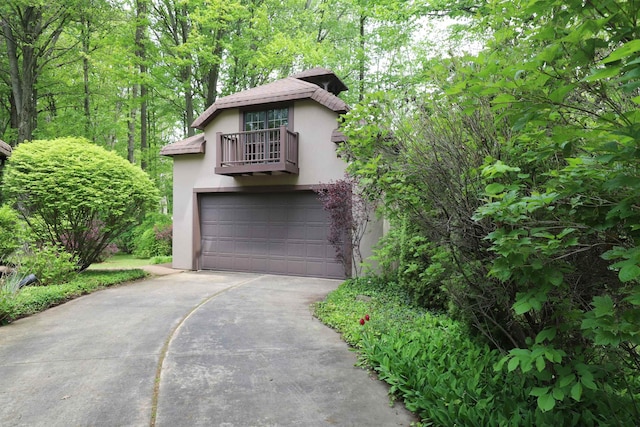 10466 W Farrand Rd, Montrose, MI 48457 - view of front of property featuring stucco siding, a balcony, driveway, and an attached garage