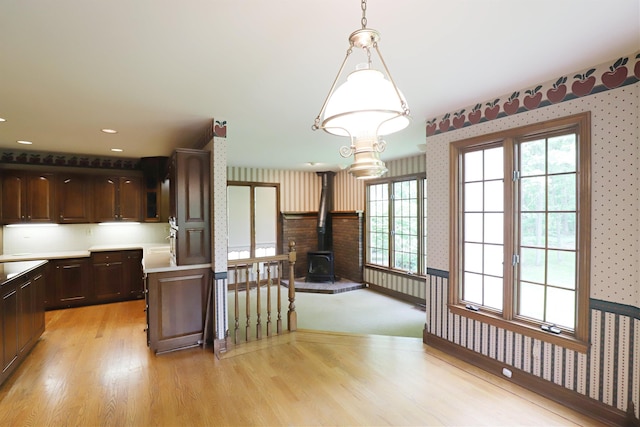 10466 W Farrand Rd, Montrose, MI 48457 - kitchen featuring wallpapered walls, a wood stove, light wood-style flooring, dark brown cabinets, and light countertops