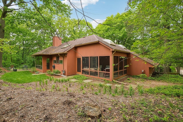 3805 Penberton Ct, Ann Arbor, MI 48105 - back of property with a sunroom, a chimney, and a shingled roof