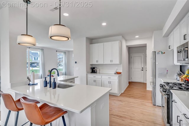8811 Pioneer St, Washington, MI 48094 - kitchen featuring stainless steel microwave, a sink, gas range, light wood finished floors, and a kitchen bar
