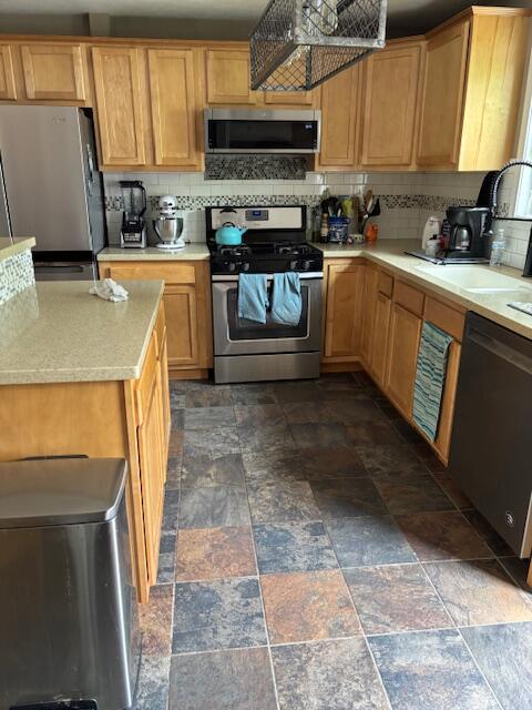 209 S Lake Ave, Fremont, MI 49412 - kitchen featuring appliances with stainless steel finishes, stone finish floors, light countertops, and backsplash