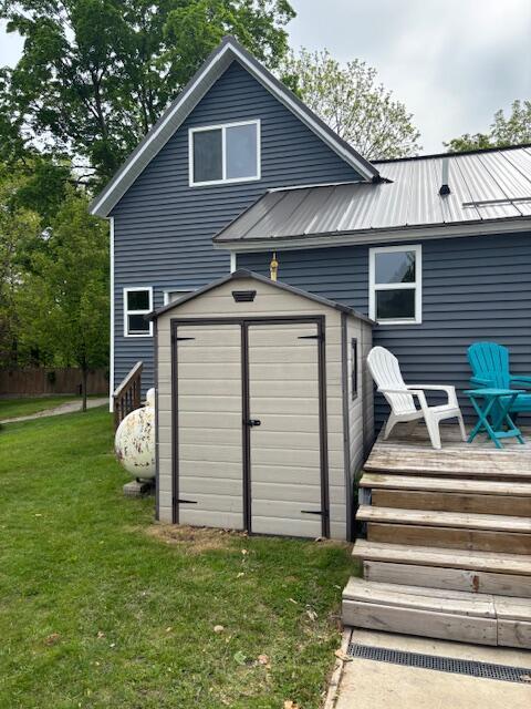 209 S Lake Ave, Fremont, MI 49412 - rear view of house featuring a deck, a lawn, and metal roof