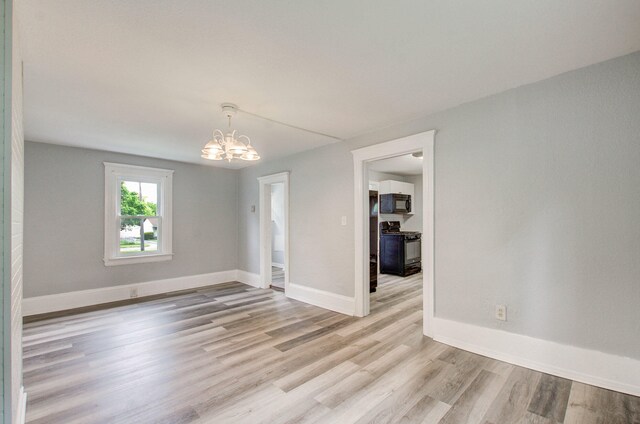 157 E Mansion St, Jackson, MI 49203 - unfurnished room featuring light wood-style floors, a chandelier, and baseboards
