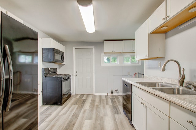 157 E Mansion St, Jackson, MI 49203 - kitchen with black appliances, a sink, light wood-style flooring, and white cabinetry