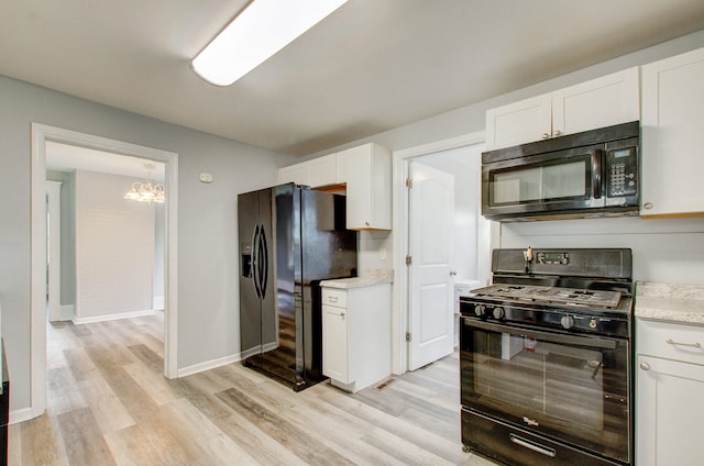 157 E Mansion St, Jackson, MI 49203 - kitchen featuring black appliances, light wood-style floors, a chandelier, and white cabinets