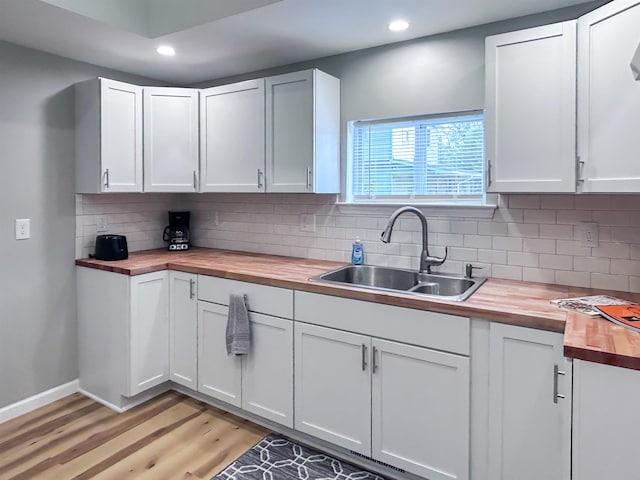 5098 N Center Rd, Flint, MI 48506 - kitchen with wood counters, a sink, tasteful backsplash, light wood-type flooring, and white cabinetry
