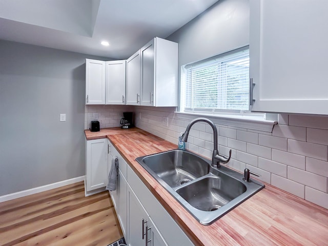 5098 N Center Rd, Flint, MI 48506 - kitchen featuring wood counters, a sink, white cabinets, decorative backsplash, and light wood-style floors