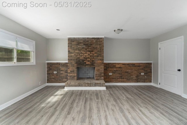 16565 Winston St, Detroit, MI 48219 - unfurnished living room featuring wood finished floors, baseboards, brick wall, and a fireplace