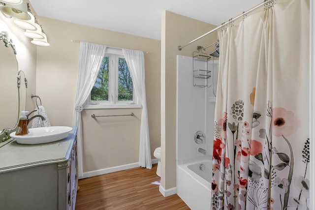 7938 E Dr N, Battle Creek, MI 49014 - bathroom featuring vanity, wood finished floors, shower / tub combo, baseboards, and toilet