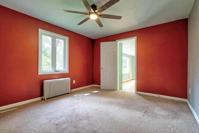 7938 E Dr N, Battle Creek, MI 49014 - carpeted spare room with radiator heating unit, plenty of natural light, a ceiling fan, baseboards, and a textured ceiling