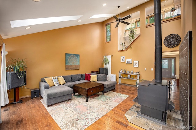 1295 Kern Rd, Oakland, MI 48363 - living area with a wood stove, a skylight, high vaulted ceiling, a ceiling fan, and wood finished floors