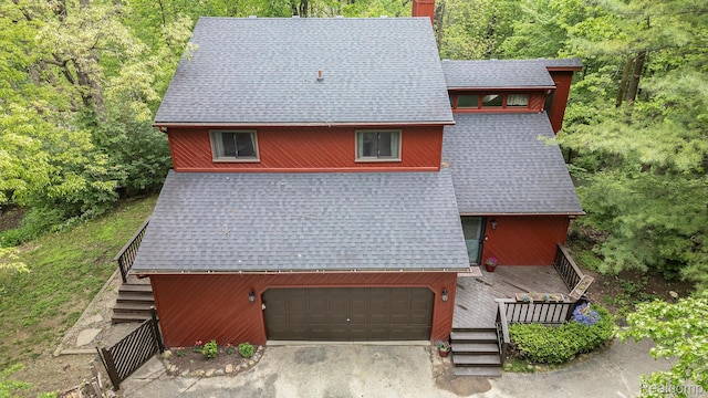 1295 Kern Rd, Oakland, MI 48363 - view of front facade with roof with shingles, stairway, a deck, an attached garage, and a view of trees
