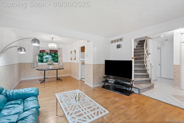 9495 Continental Dr, Taylor, MI 48180 - living room featuring wainscoting, a chandelier, wallpapered walls, stairway, and wood finished floors