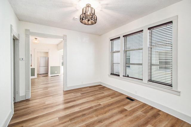 224 Spencer St NE, Grand Rapids, MI 49505 - spare room with a chandelier, light wood-style flooring, and baseboards