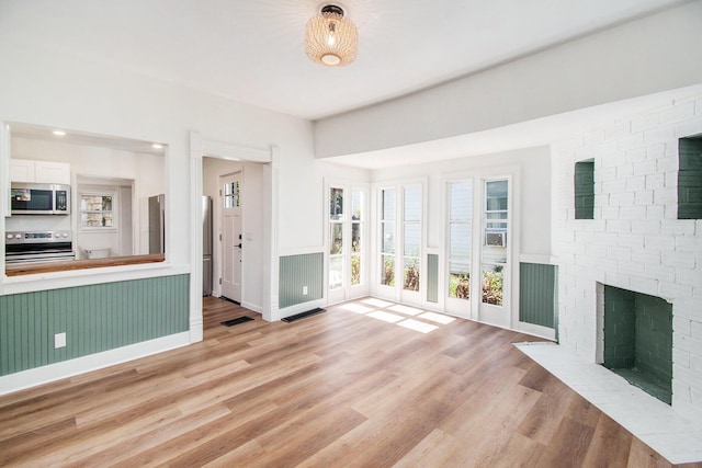 224 Spencer St NE, Grand Rapids, MI 49505 - unfurnished living room featuring light wood-type flooring and a brick fireplace