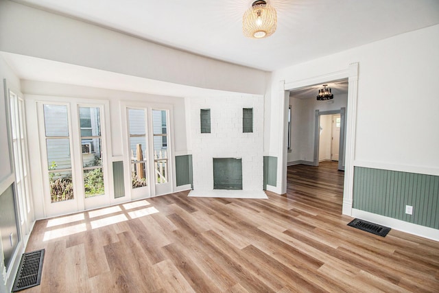 224 Spencer St NE, Grand Rapids, MI 49505 - unfurnished living room with light wood-type flooring, a brick fireplace, baseboards, and a chandelier