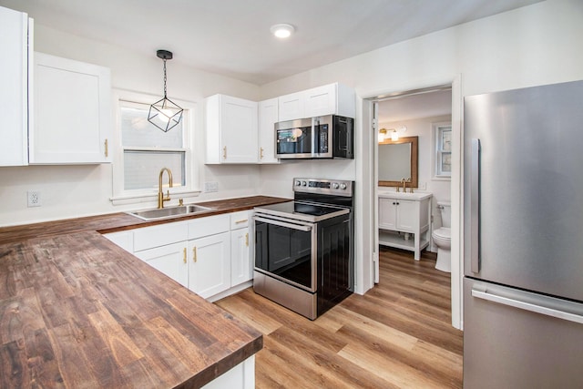 224 Spencer St NE, Grand Rapids, MI 49505 - kitchen with stainless steel appliances, a sink, butcher block counters, and white cabinets