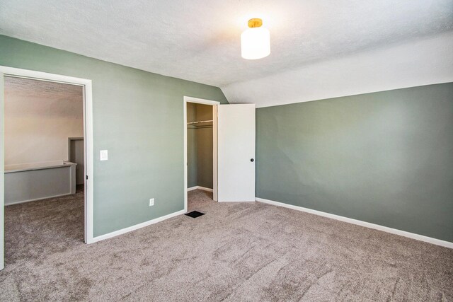 224 Spencer St NE, Grand Rapids, MI 49505 - unfurnished bedroom featuring carpet flooring, vaulted ceiling, baseboards, a closet, and a textured ceiling