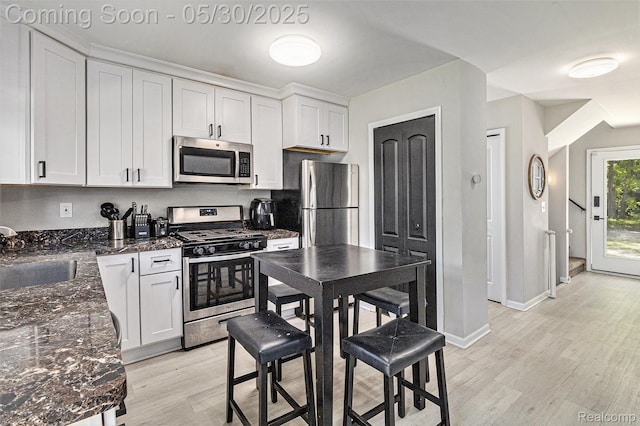 9475 Beechcrest Dr, White Lake, MI 48386 - kitchen with appliances with stainless steel finishes, a sink, light wood-type flooring, white cabinetry, and dark stone counters