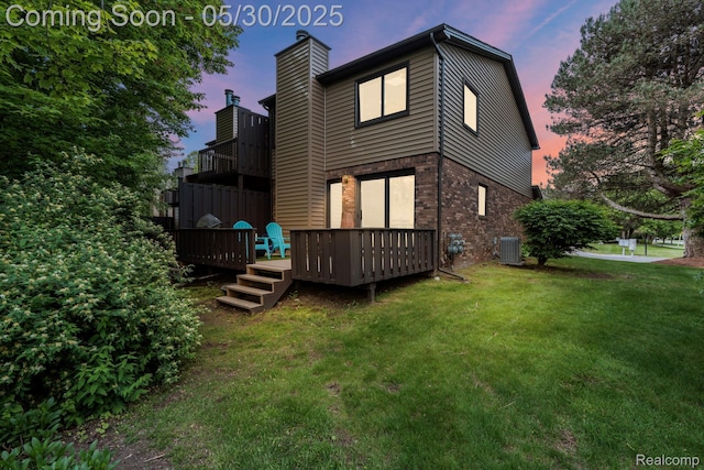 50820 Marsha Ln, New Baltimore, MI 48047 - back of house at dusk featuring central AC, brick siding, a yard, a chimney, and a wooden deck
