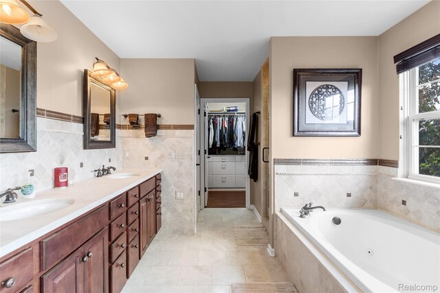 6241 Sapphire Ct, Grand Blanc, MI 48439 - full bathroom featuring double vanity, a jetted tub, tile walls, a spacious closet, and tile patterned flooring