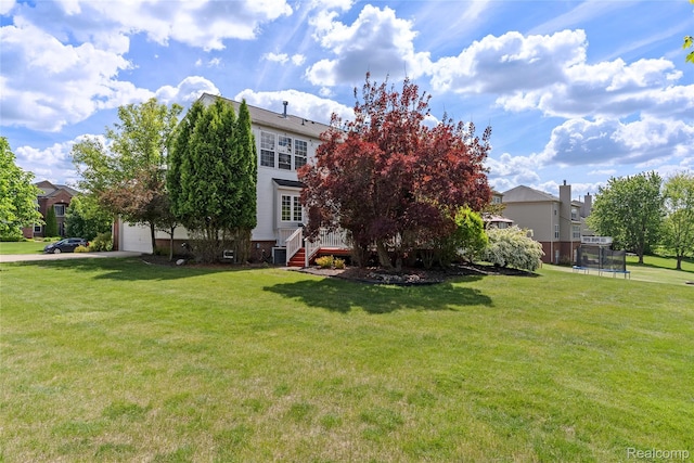 6241 Sapphire Ct, Grand Blanc, MI 48439 - back of house with a trampoline, a garage, a yard, and central AC