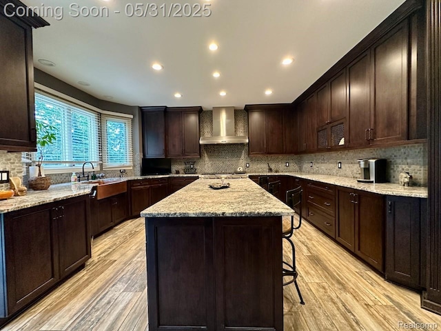 52006 Finch Ct, Shelby Twp, MI 48315 - kitchen featuring wall chimney exhaust hood, a kitchen island, light wood finished floors, a breakfast bar area, and recessed lighting