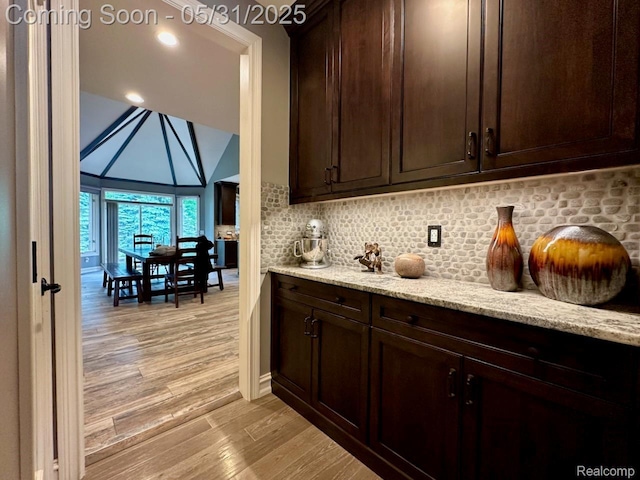 52006 Finch Ct, Shelby Twp, MI 48315 - kitchen with light wood finished floors, dark brown cabinets, light stone counters, tasteful backsplash, and high vaulted ceiling