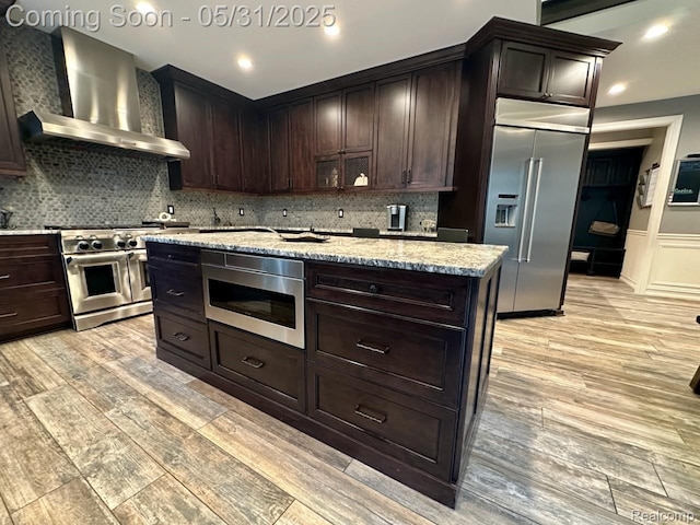 52006 Finch Ct, Shelby Twp, MI 48315 - kitchen featuring premium appliances, wall chimney exhaust hood, light wood-type flooring, light stone counters, and backsplash
