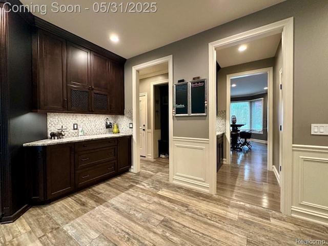 52006 Finch Ct, Shelby Twp, MI 48315 - kitchen featuring light wood-style floors, dark brown cabinetry, backsplash, wainscoting, and light stone countertops