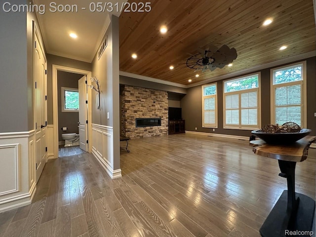 52006 Finch Ct, Shelby Twp, MI 48315 - unfurnished living room with ornamental molding, a stone fireplace, wainscoting, a ceiling fan, and dark wood-type flooring