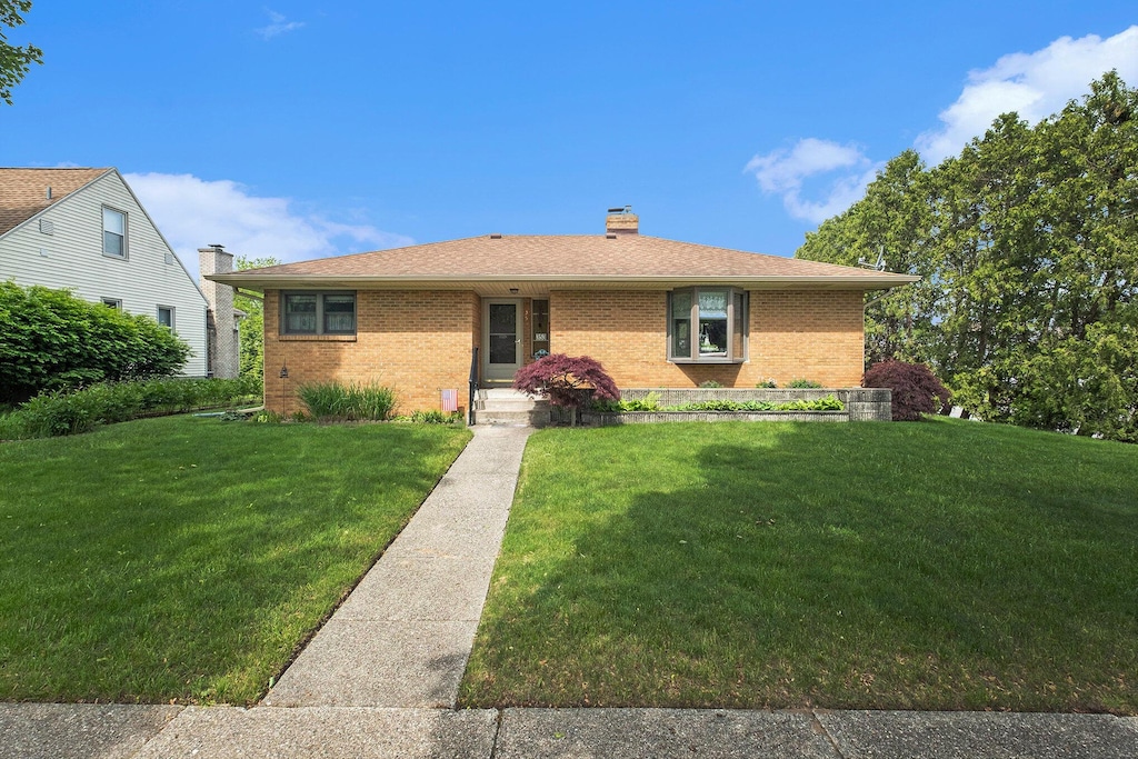 353 Alten Ave NE, Grand Rapids, MI 49503 - view of front of house with brick siding, a front lawn, and a chimney