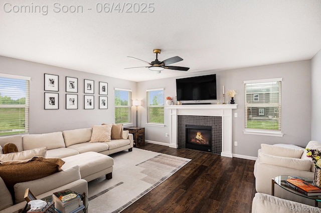 13210 River Bend Dr, Linden, MI 48451 - living room featuring dark wood-style flooring, a tiled fireplace, plenty of natural light, and a ceiling fan
