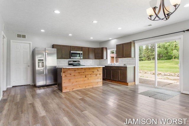 4403 4th St, Caledonia, MI 49316 - kitchen with appliances with stainless steel finishes, dark brown cabinets, decorative backsplash, light countertops, and a kitchen island